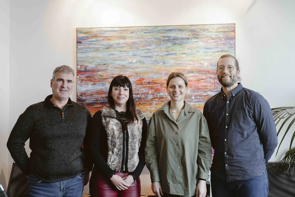 4 Projektteilnehmer vor einem großen bunten Bild im Hintergrund